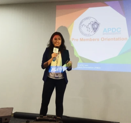 Tracy presenting with a microphone beside a projected presentation
